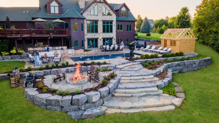Luxury backyard landscaping with pool, fire pit, and stone retaining walls. Outdoor living space with custom design.