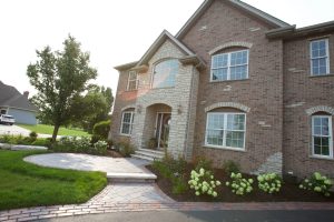 Brick house exterior with stone accents, arched windows, and landscaped front yard. Curb appeal.