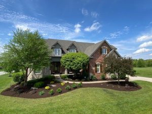 Beautiful brick house with manicured lawn, landscaping, and blue sky. Real estate.