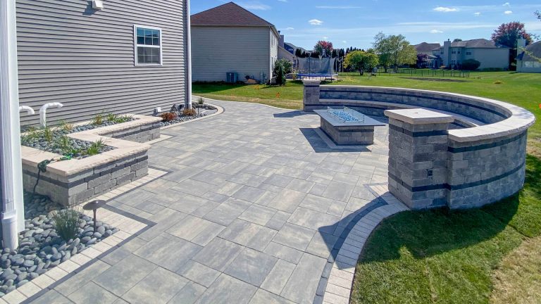 Residential landscaping with brick paver patio and firepit installation. Outdoor living space.