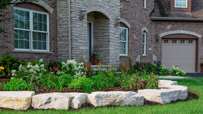 Residential home landscape. Garden design with stone borders and flower bed. Commercial landscaping.