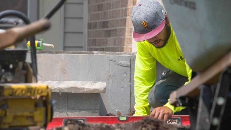 Residential landscape design and installation. Landscaper working on stone steps. Commercial landscaping.