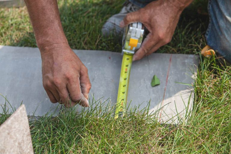 Residential landscape design installation. Measuring stone for commercial landscaping with tape measure.