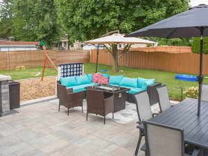 Photo of a Beautiful Outdoor Living Area with chairs, table, benches, fire table, and swing set on a brick paver patio surface