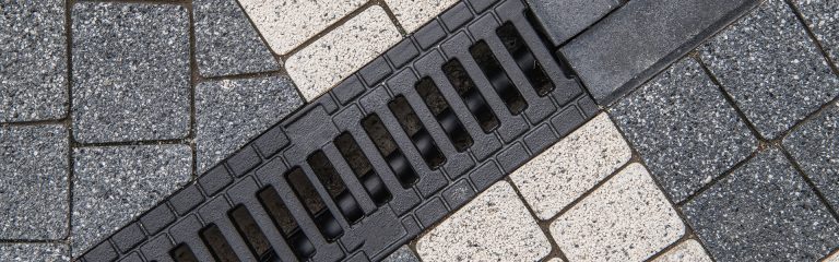 Brick driveway with water drain. Drainage services for paved surfaces.