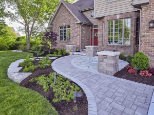 Brick paver walkway landscaping with plantings. Home exterior with stone pathway and garden.