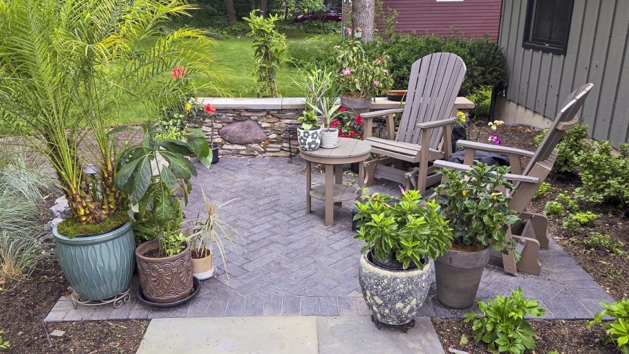 Beautiful brick paver patio design with Adirondack chairs and potted plants. Backyard landscaping. Beautiful brick paver patio design with Adirondack chairs and potted plants. Backyard landscaping.