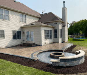 Custom patio design with paver patio, fire pit, and seat wall. Backyard landscaping and outdoor living space.
